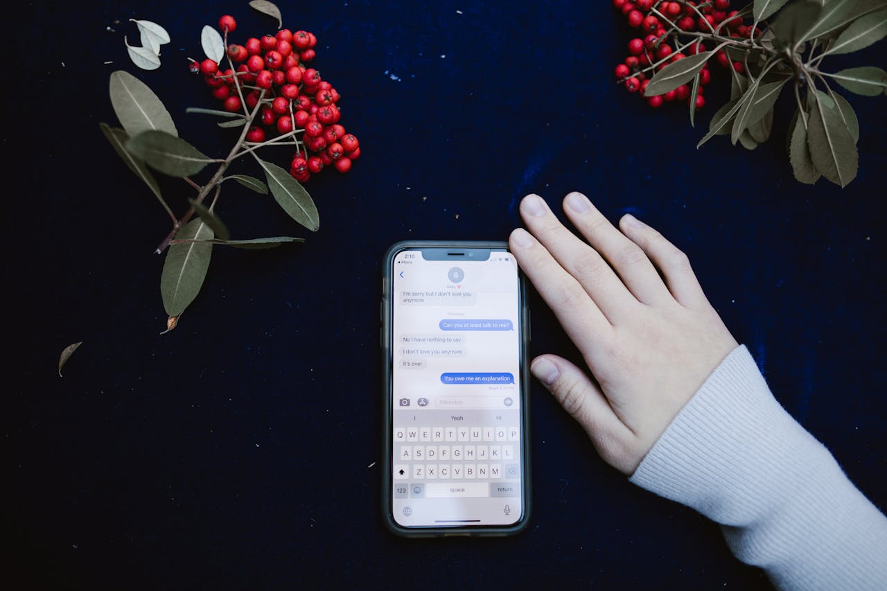 services-02 A hand beside a smartphone showing a text message conversation, surrounded by red berries.