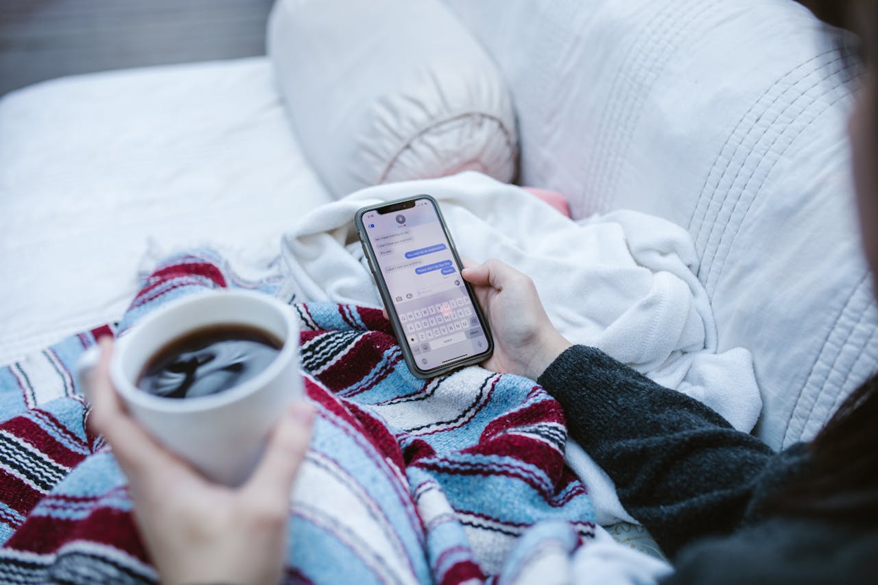 Mastering the First Impression: Your intriguing post title goes here Person relaxing indoors with coffee and smartphone, texting in a cozy setting.